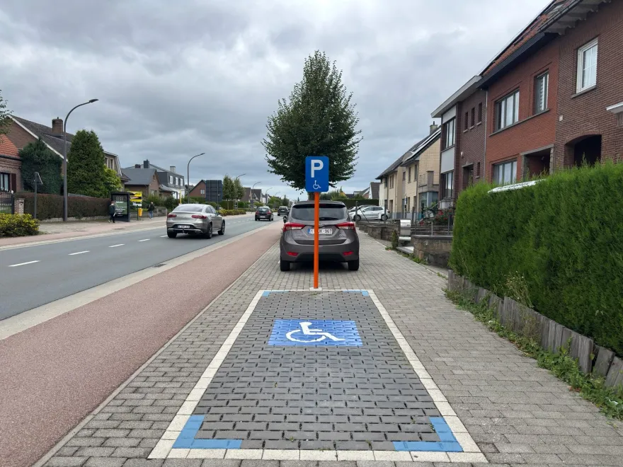 Emplacement de stationnement marqué au sol d'un fauteuil roulant bleu, avec le signal correspondant