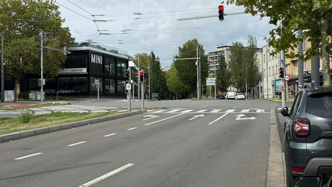 Feu rouge à un carrefour, avec un passage pour piétons et des flèches de sélection au sol