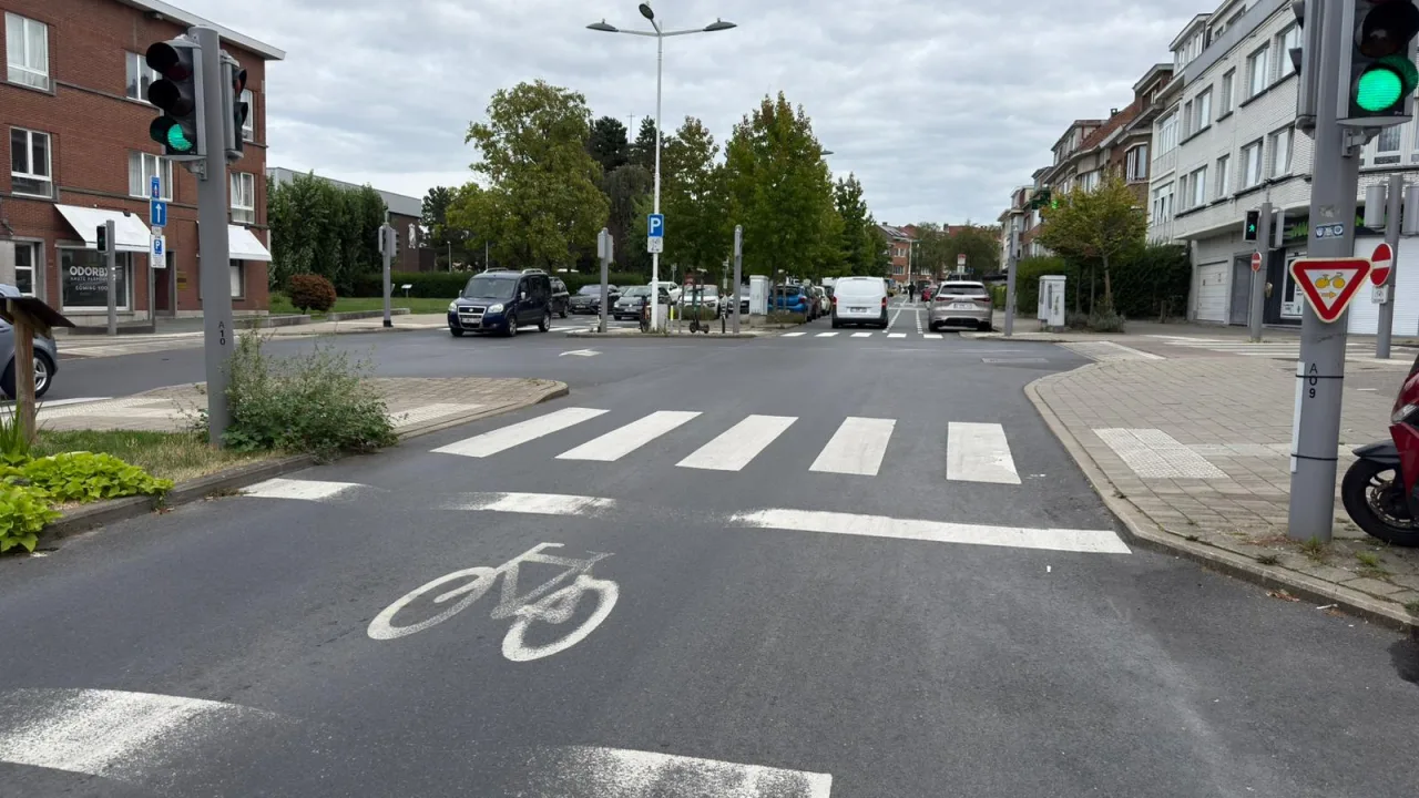 Panneau triangulaire au vélo portant deux flèches, à un carrefour à feux