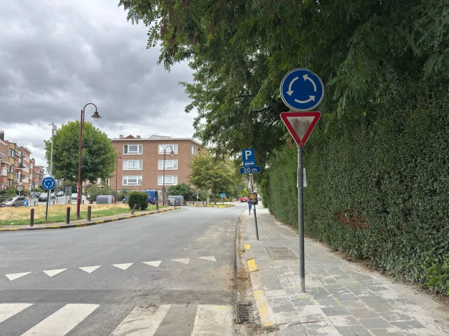 Signal de sens giratoire obligatoire au-dessus d'un cédez-le-passage, avec des triangles blancs peints au sol