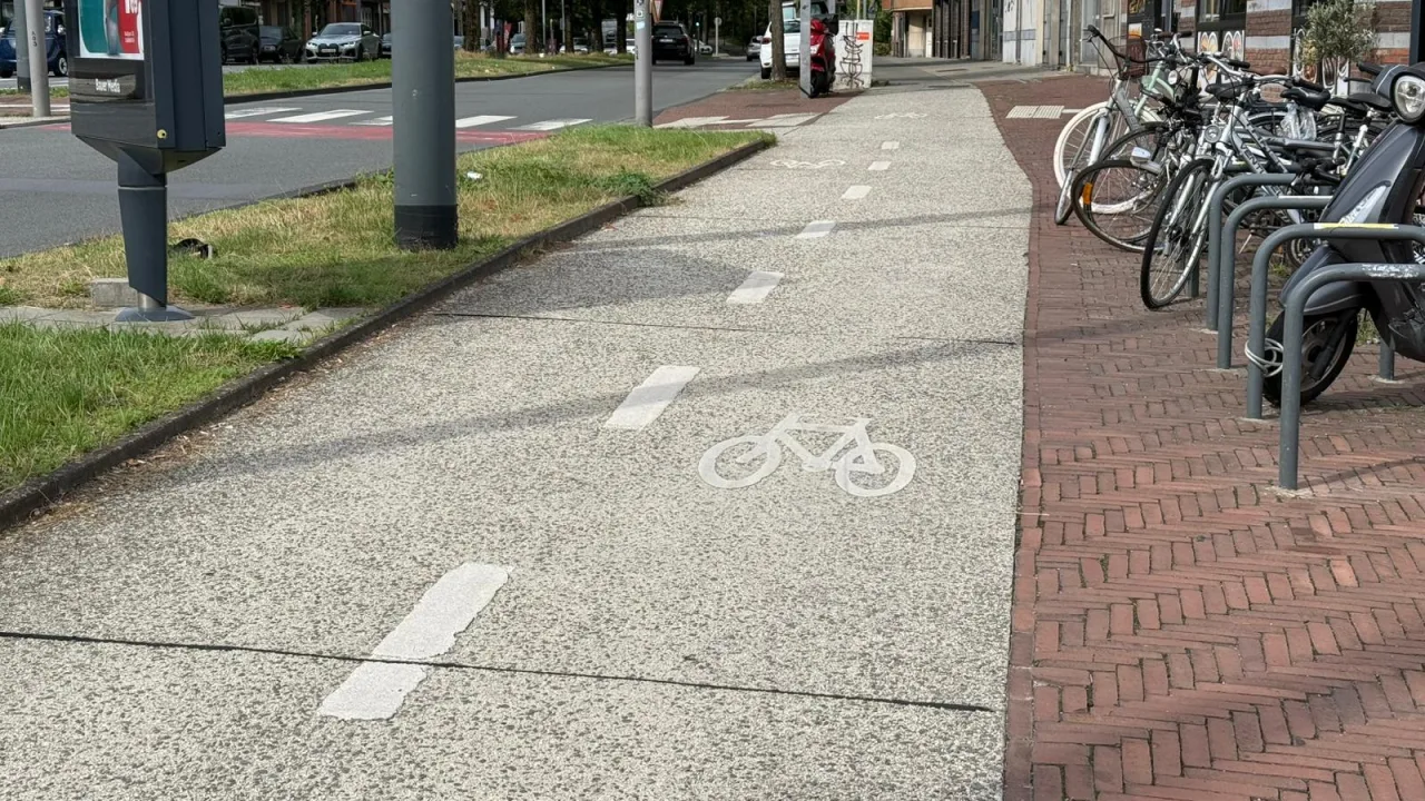 Piste cyclable bordée de deux lignes blanches discontinues, avec un vélo peint au sol