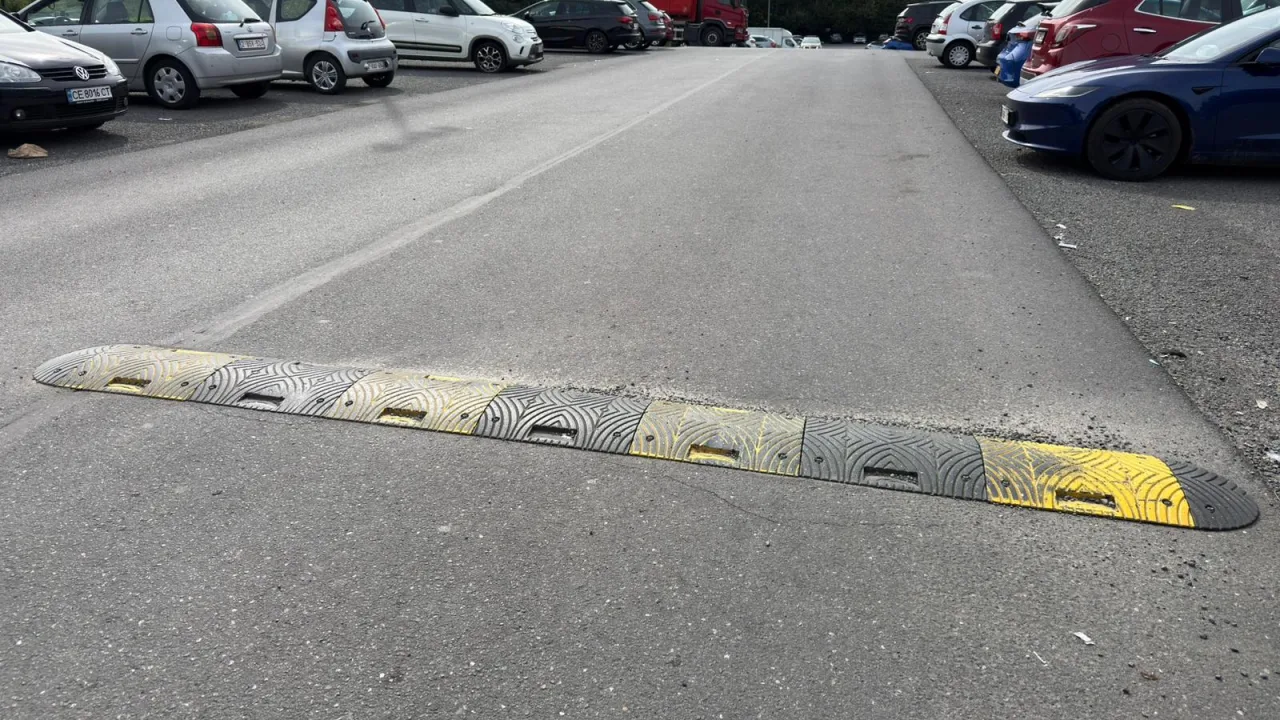 Ralentisseur en caoutchouc jaune et noir en travers d'une allée de parking