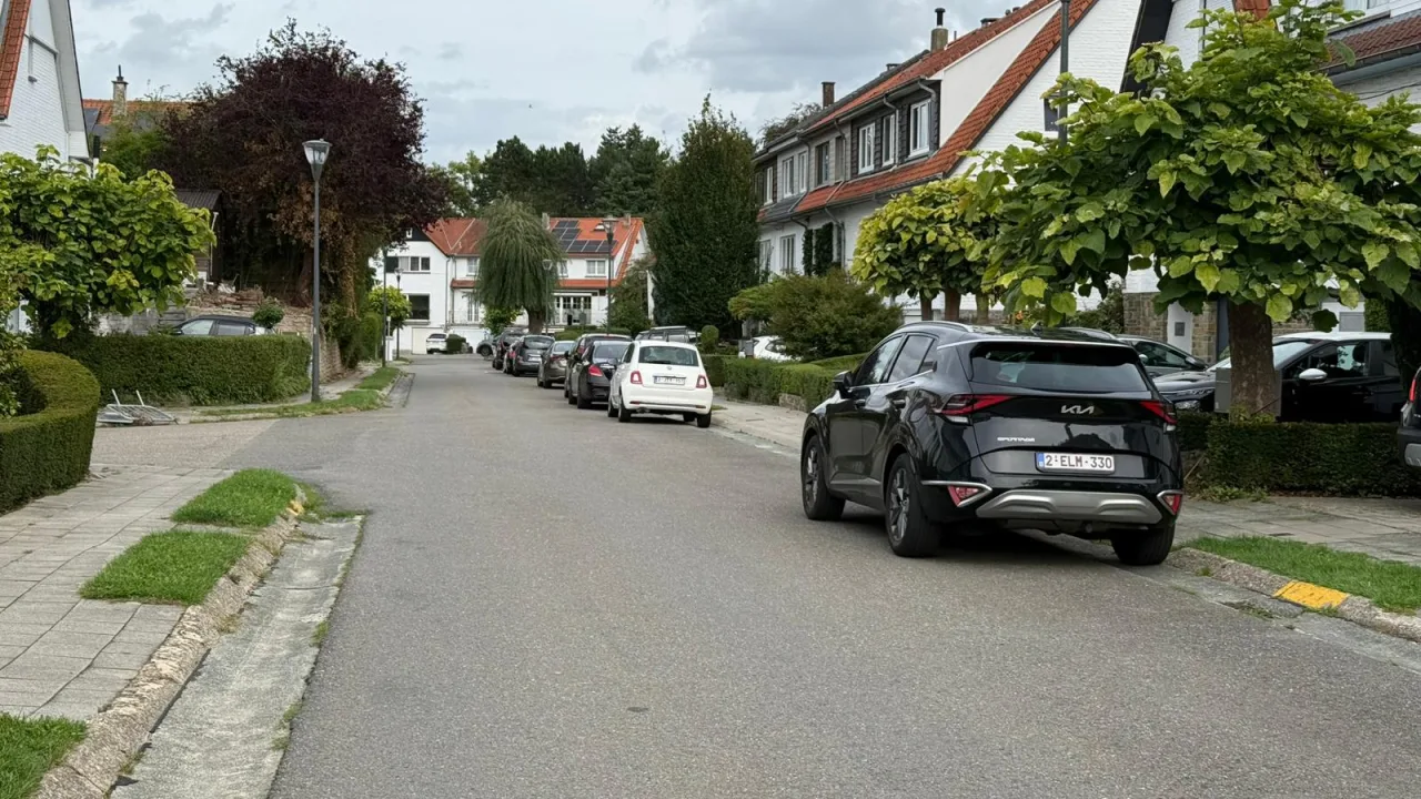 Rue résidentielle sans signalisation, avec des voitures en stationnement