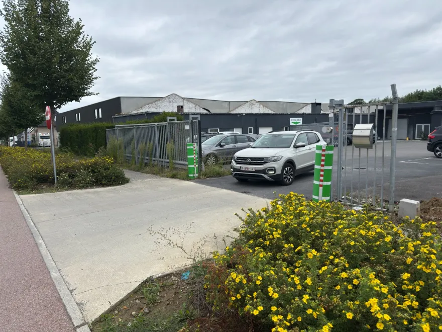 Voiture blanche s'apprêtant à sortir d'un parking privé et à traverser une piste cyclable rouge