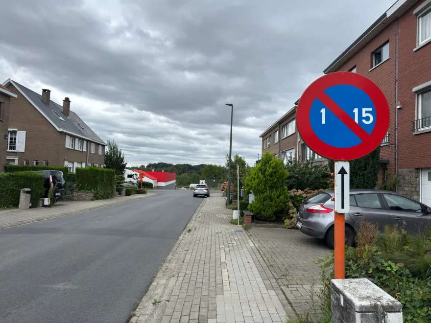 Signal de stationnement alterné portant les chiffres 1 et 15, au bord d'une rue résidentielle