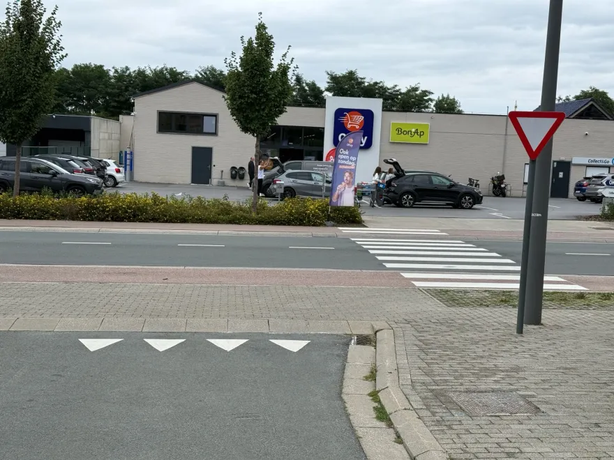 Débouché d'une voie sur une chaussée, marqué de triangles blancs, avec un passage pour piétons et un signal cédez-le-passage