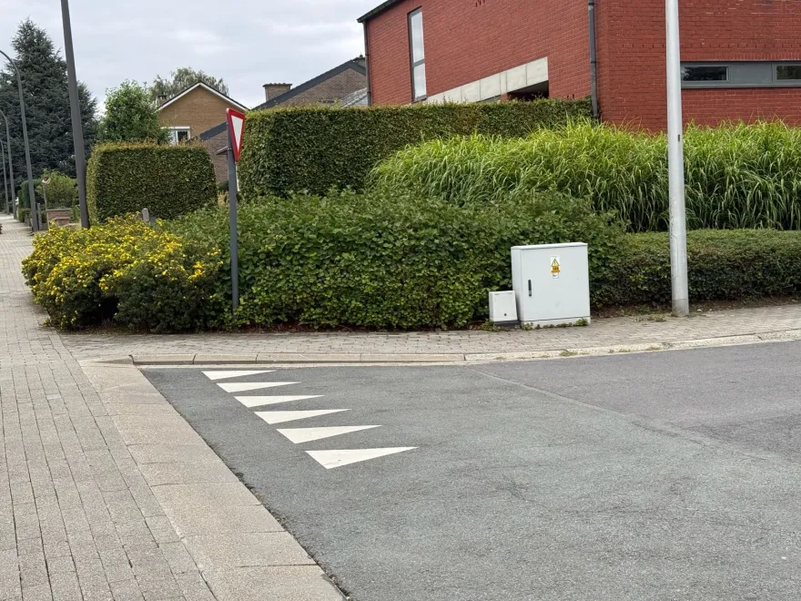 Sortie d'une rue latérale marquée de triangles blancs au sol, avec un signal cédez-le-passage au coin