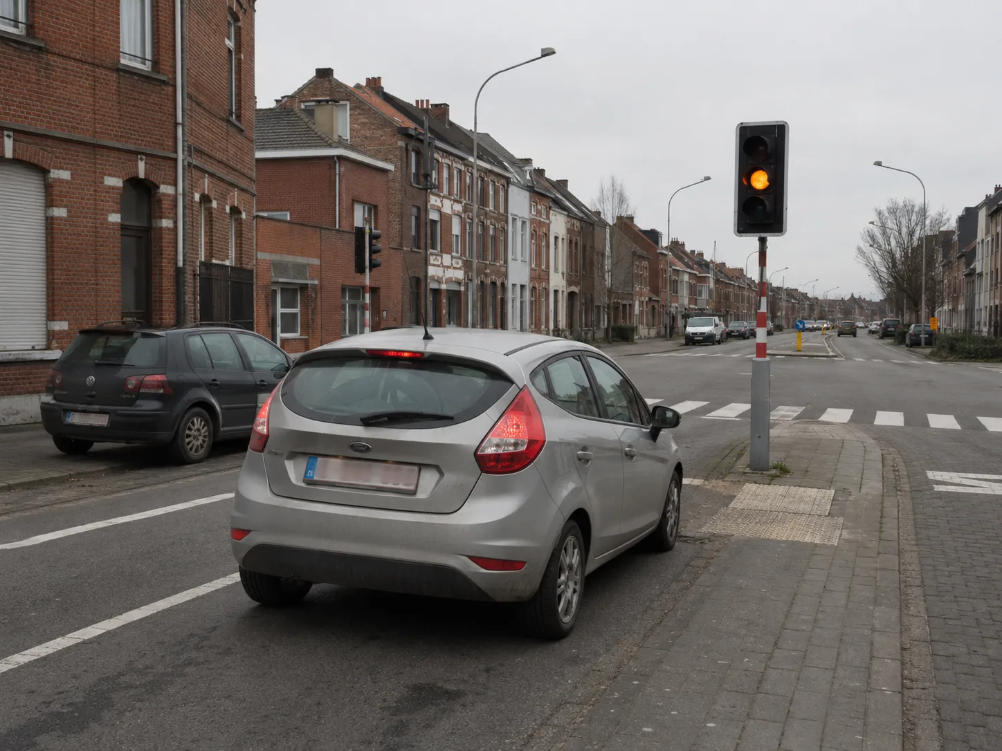Feu tricolore belge sur poteau montrant un orange clignotant au centre